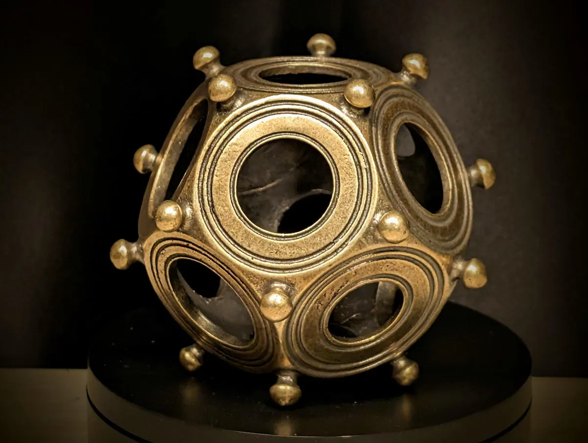 Cast brass dodecahedron, front view showing ringed holes and corner knobs